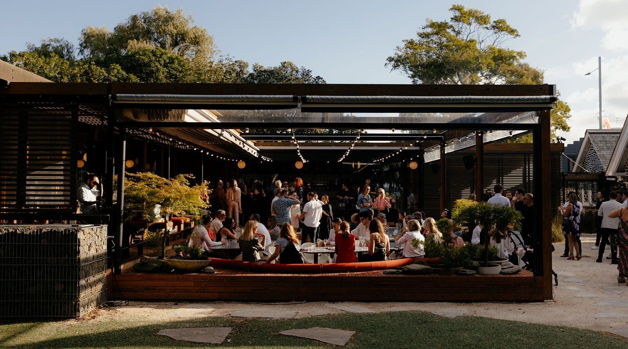 Guests gathered at an outdoor courtyard bar under festoon lights