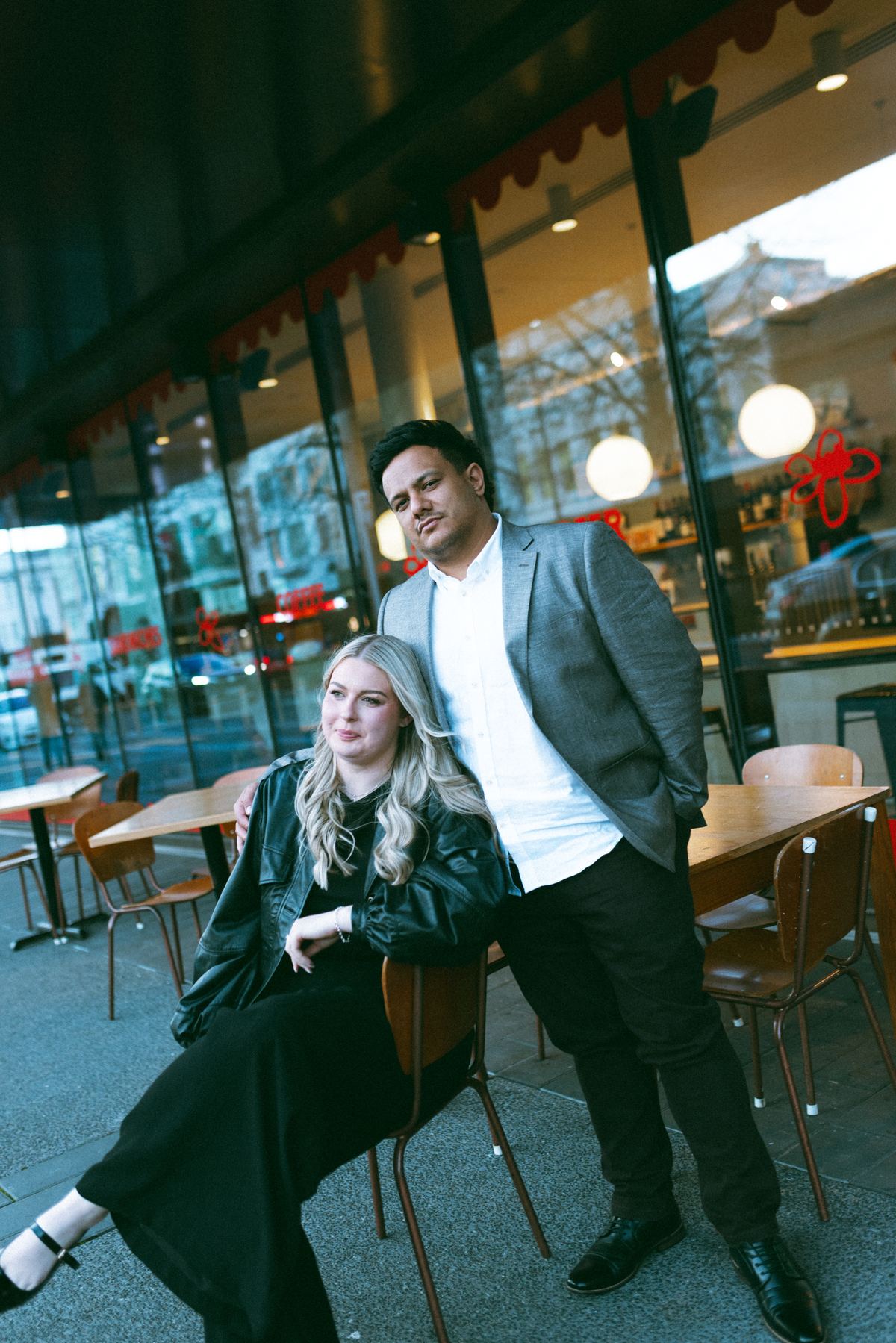 Zoe sitting at a street-side table with Tyler standing beside her