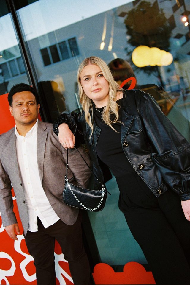 Zoe and Tyler posing on film outside a bright red shopfront