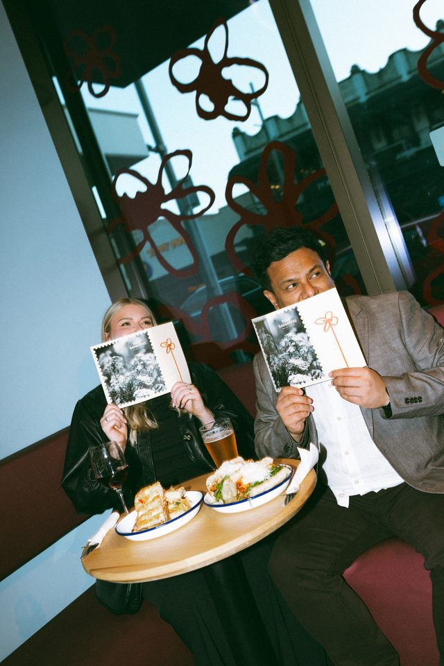 Zoe and Tyler hiding behind menus over lunch